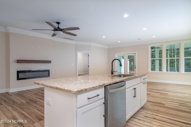 kitchen featuring a kitchen island with sink, a sink, white cabinets, open floor plan, and stainless steel dishwasher