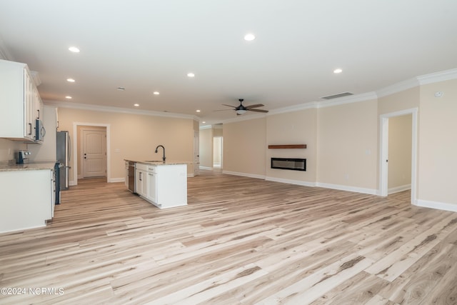 kitchen featuring a glass covered fireplace, open floor plan, white cabinetry, and an island with sink