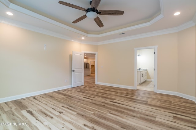 unfurnished bedroom with a raised ceiling, baseboards, crown molding, and light wood finished floors