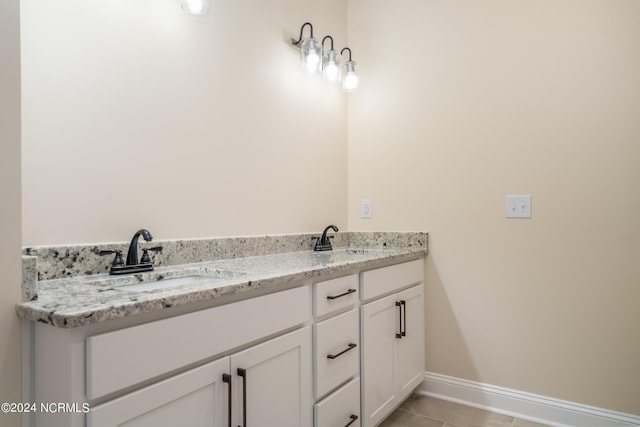 full bath featuring double vanity, baseboards, a sink, and tile patterned floors