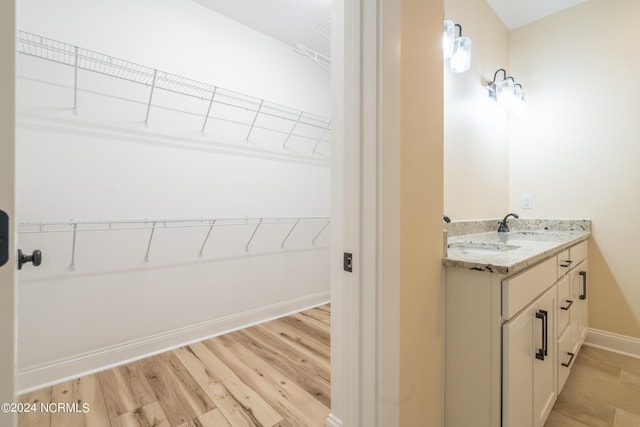 bathroom with double vanity, baseboards, a sink, and wood finished floors