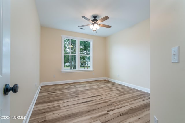 empty room with a ceiling fan, light wood-type flooring, visible vents, and baseboards