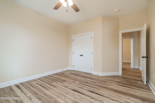 unfurnished bedroom featuring light wood-type flooring, ceiling fan, baseboards, and a closet