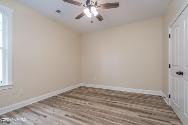 empty room featuring a ceiling fan, visible vents, light wood-style flooring, and baseboards