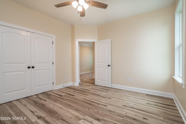 unfurnished bedroom with light wood-style floors, a ceiling fan, baseboards, and a closet