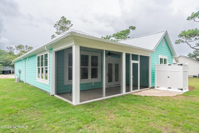 rear view of property featuring a ceiling fan, a sunroom, a yard, and metal roof