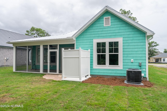 rear view of house featuring central air condition unit and a lawn