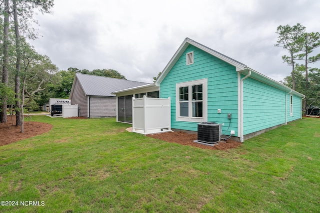 back of house with a sunroom, a lawn, and central AC