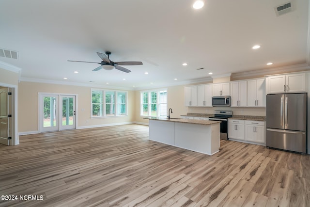 kitchen featuring stainless steel appliances, a kitchen island with sink, white cabinets, and visible vents