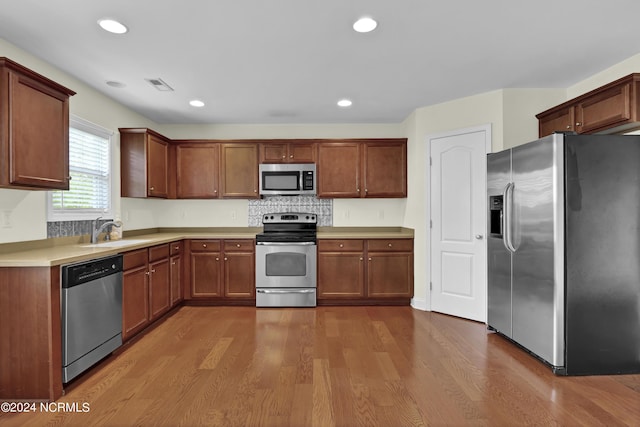 kitchen with stainless steel appliances, light countertops, visible vents, a sink, and wood finished floors