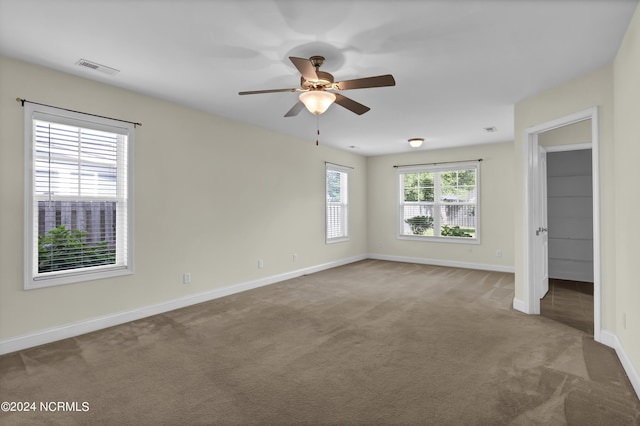 carpeted spare room with a ceiling fan, visible vents, and baseboards