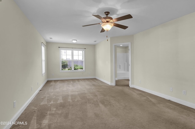 empty room with light carpet, a ceiling fan, and baseboards