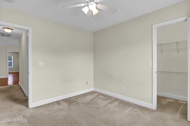 unfurnished bedroom with light carpet, a spacious closet, and visible vents