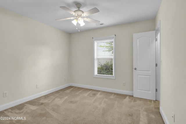 spare room featuring visible vents, ceiling fan, light carpet, and baseboards