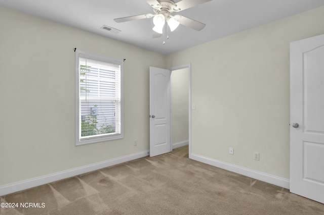 unfurnished bedroom featuring light carpet, visible vents, baseboards, and ceiling fan