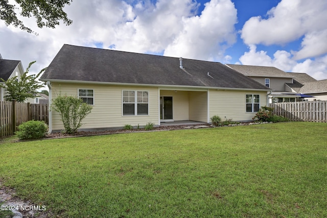 rear view of house featuring a yard, fence, and a patio