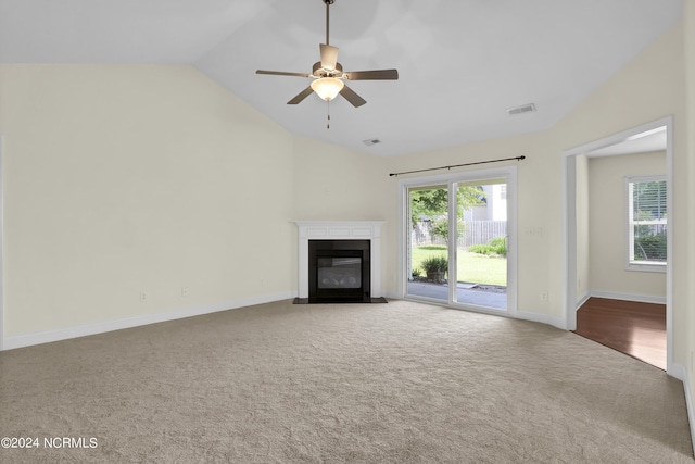 unfurnished living room featuring vaulted ceiling, carpet, a fireplace with flush hearth, and visible vents