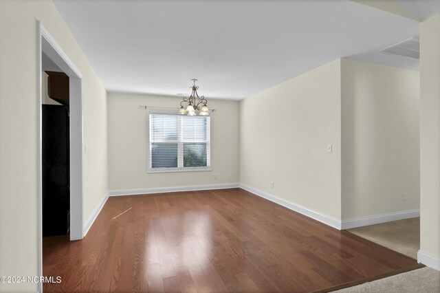 unfurnished dining area with baseboards, wood finished floors, and a notable chandelier