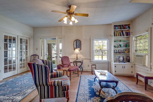 living room with french doors, cooling unit, light hardwood / wood-style flooring, ceiling fan, and built in shelves