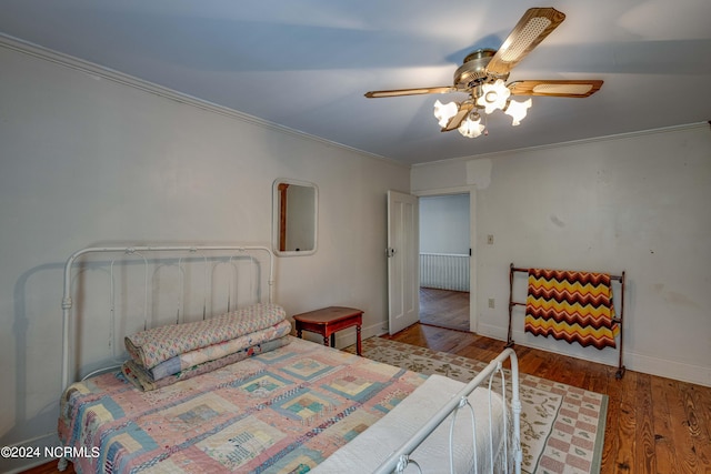 bedroom featuring hardwood / wood-style floors, crown molding, and ceiling fan