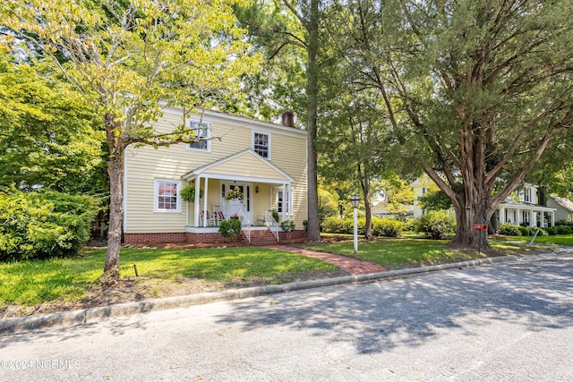 view of front of home with covered porch and a front lawn