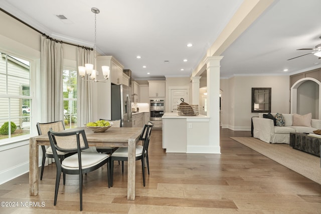 dining area with crown molding, ceiling fan, decorative columns, and light wood-type flooring