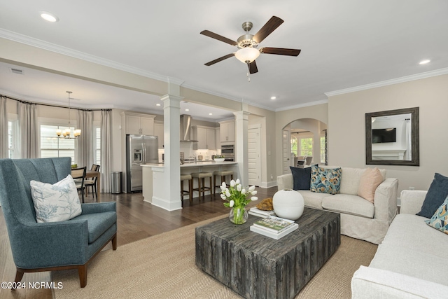 living room featuring ceiling fan with notable chandelier, ornamental molding, and dark hardwood / wood-style floors