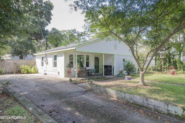 single story home with driveway, fence, a porch, and a front yard