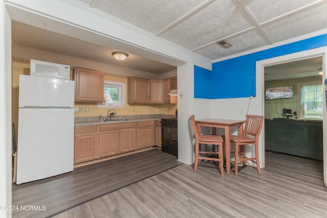 kitchen with white appliances, wood finished floors, a sink, visible vents, and light countertops