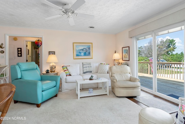 carpeted living room featuring a textured ceiling and ceiling fan