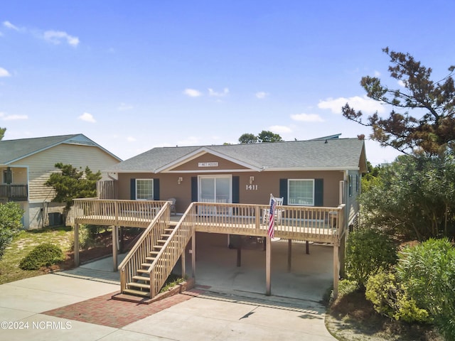 view of front of house featuring a carport, roof with shingles, driveway, and stairs