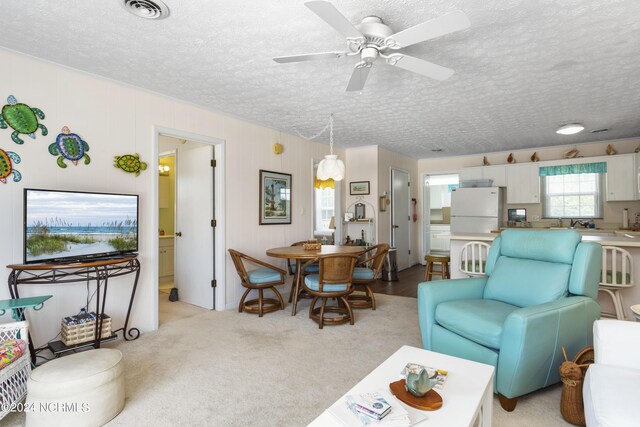 carpeted living room with ceiling fan and a textured ceiling