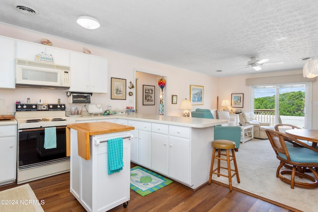 kitchen with white cabinetry, white appliances, a center island, dark hardwood / wood-style floors, and a breakfast bar area