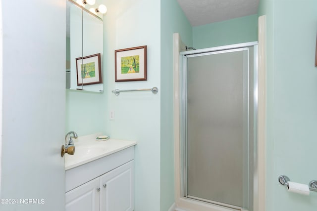 bathroom featuring walk in shower, a textured ceiling, and vanity