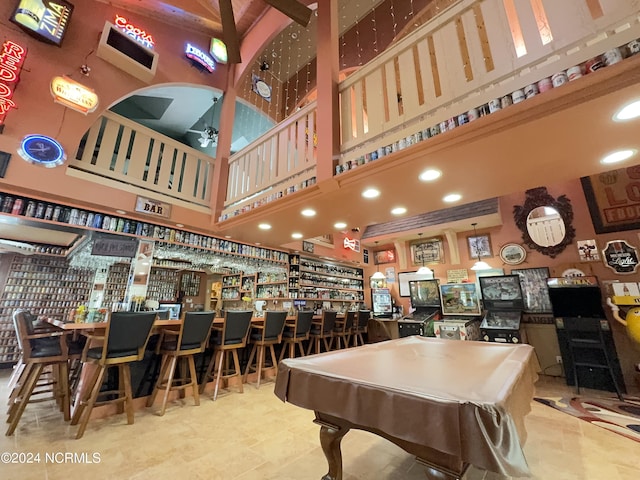 rec room with a bar, billiards, a towering ceiling, and a ceiling fan