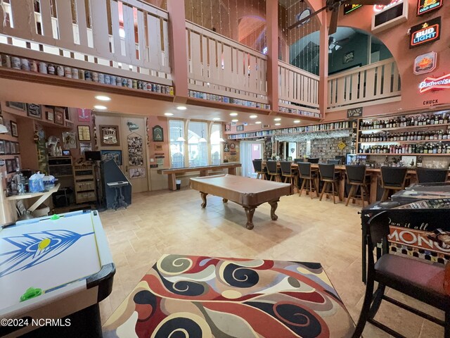 game room with tile patterned flooring, bar area, billiards, and a towering ceiling