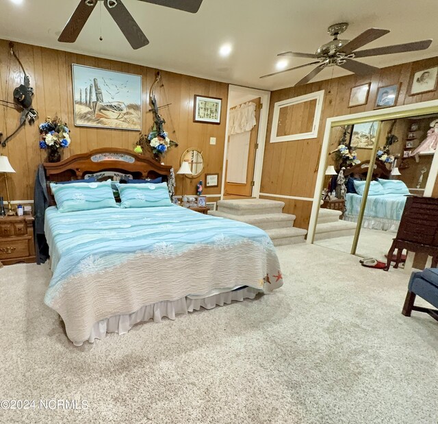 carpeted bedroom featuring ceiling fan and wooden walls