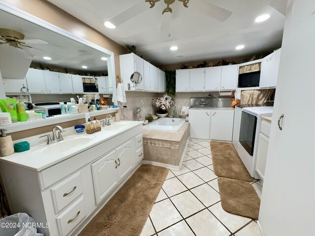 kitchen with ceiling fan, washing machine and clothes dryer, white cabinetry, sink, and light tile patterned flooring