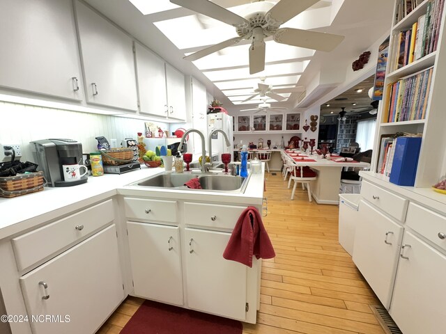 kitchen with sink, ceiling fan, light hardwood / wood-style floors, and white cabinetry