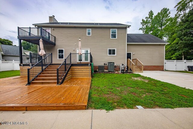 rear view of property with a yard, a wooden deck, a balcony, and central AC unit