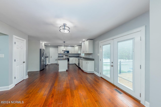 kitchen featuring appliances with stainless steel finishes, a kitchen island, white cabinetry, and dark hardwood / wood-style floors