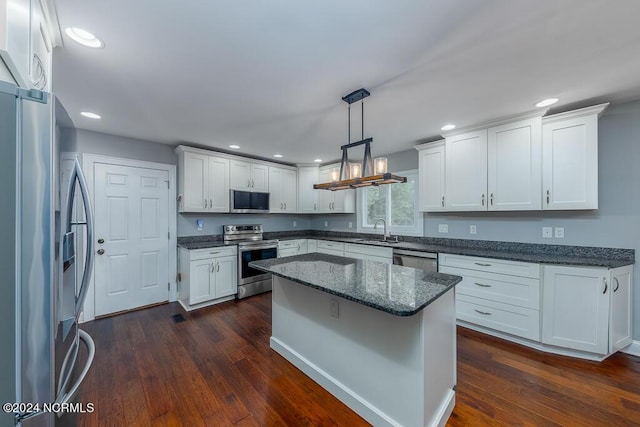 kitchen with stainless steel appliances, white cabinetry, sink, and decorative light fixtures