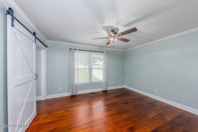 unfurnished bedroom featuring ornamental molding, a barn door, ceiling fan, and dark hardwood / wood-style flooring