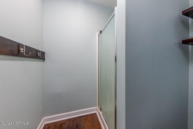 bathroom with hardwood / wood-style flooring and a shower with shower door