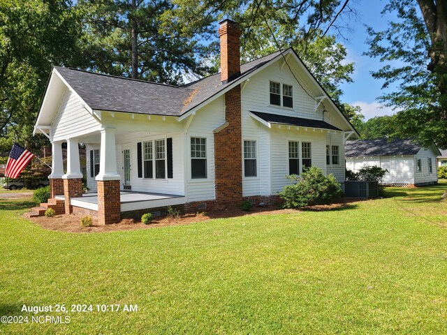 rear view of property featuring a yard and cooling unit