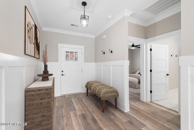 foyer entrance featuring visible vents, crown molding, and wood finished floors