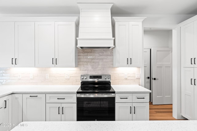 4039 Pintail Ave, Shallotte, NC 28470 - kitchen with electric stove, wall chimney range hood, white cabinets, tasteful backsplash, and light stone countertops