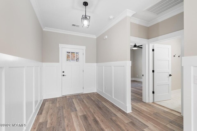 foyer entrance featuring visible vents, crown molding, and wood finished floors