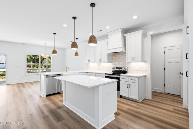 4039 Pintail Ave, Shallotte, NC 28470 - kitchen with appliances with stainless steel finishes, custom exhaust hood, a peninsula, light wood-style flooring, and a center island