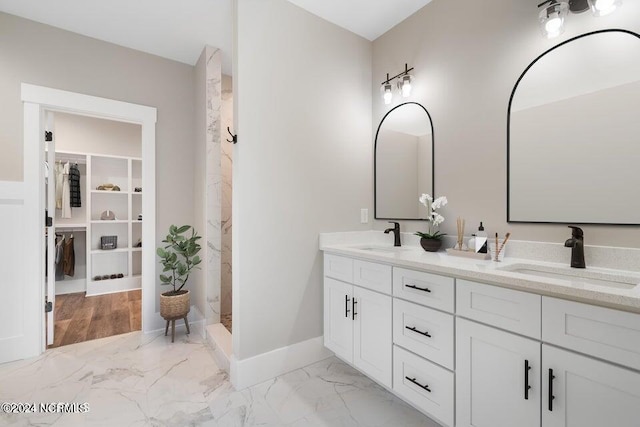 bathroom with double vanity, marble finish floor, a marble finish shower, and a sink